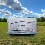 A Camec branded camper trailer cover parked on grass with a cloudy sky in the background.