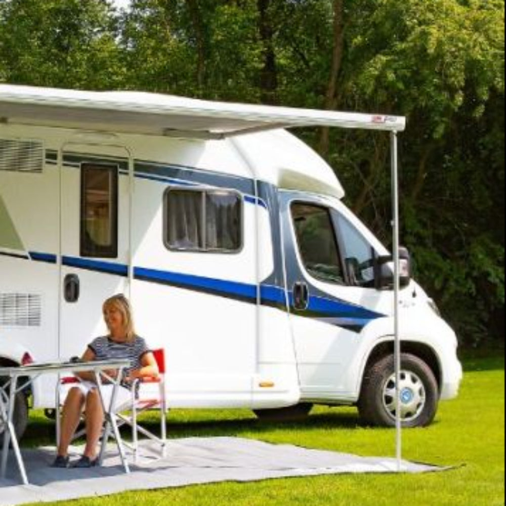 An extended Fiamma F45 S awning providing shade over an outdoor seating area next to a campervan.