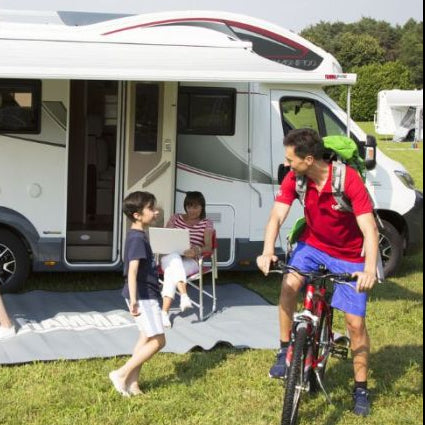 Family with children under a Fiamma Awning in a park setting