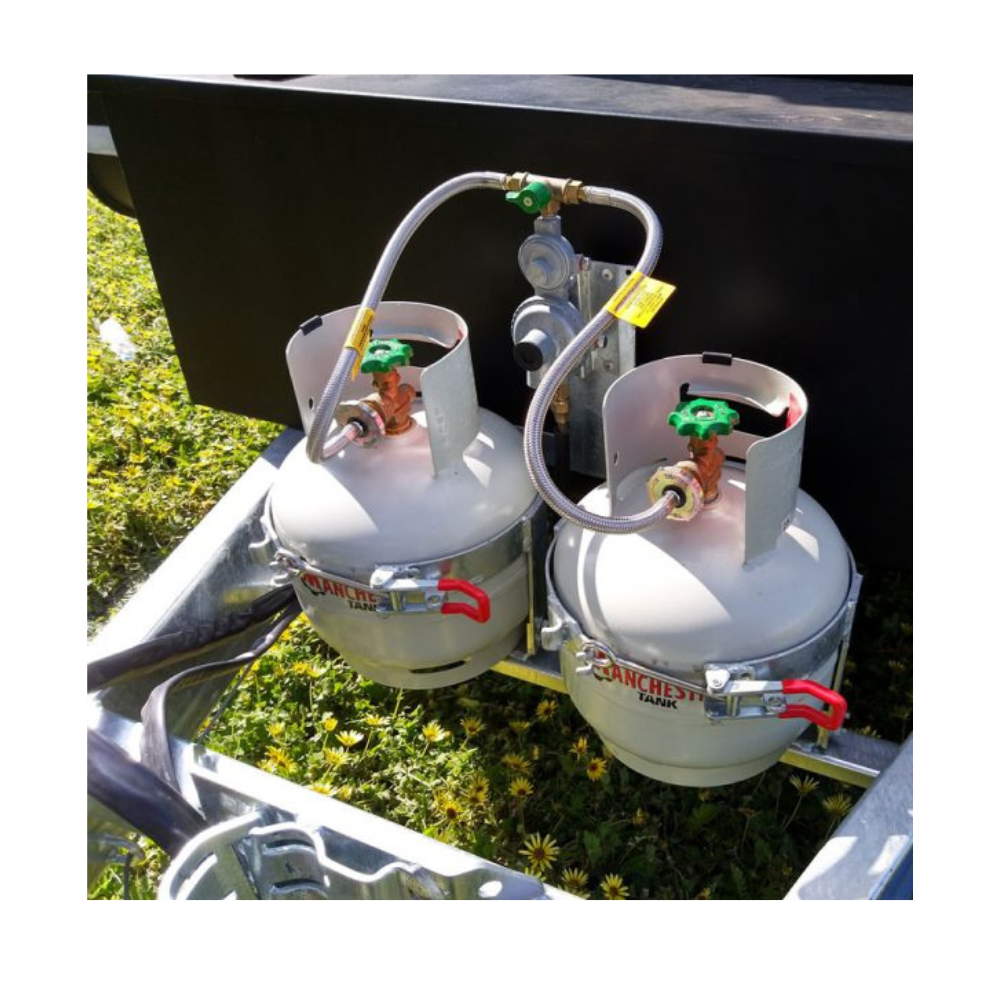 Two propane tanks attached to a vehicle with grass and flowers in the background.
