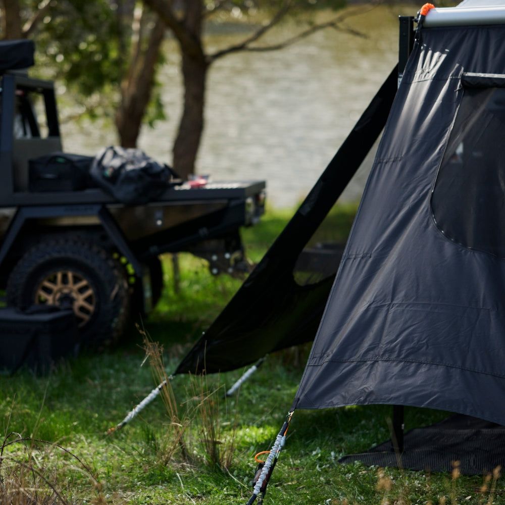Black awning set up outdoors with a vehicle in the background